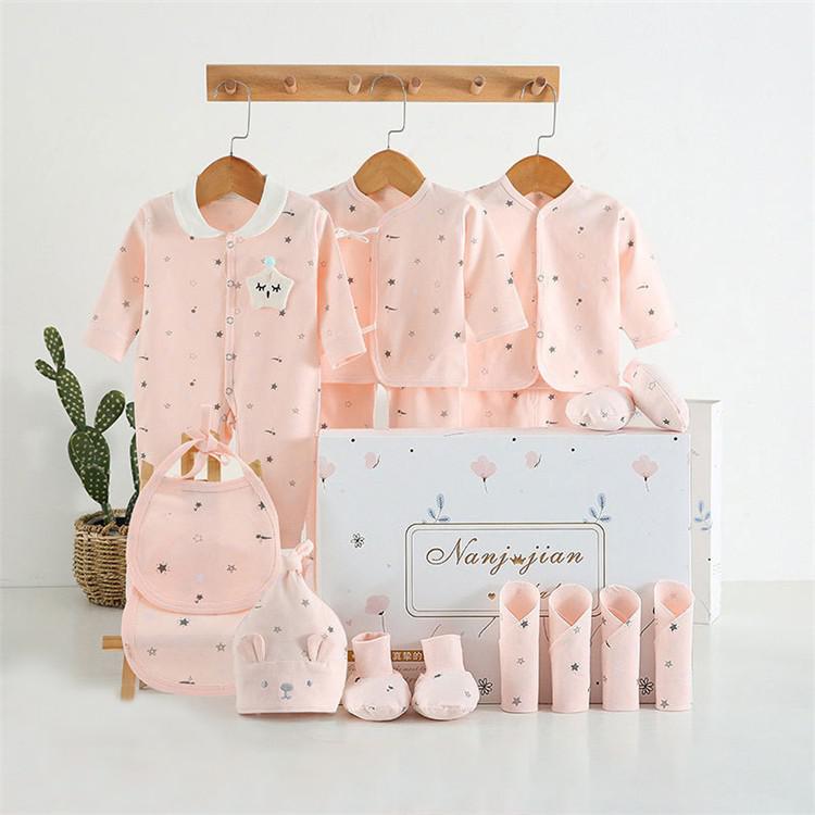 Baby clothing set with pink outfits, hats, and socks displayed on hangers against a white background.
