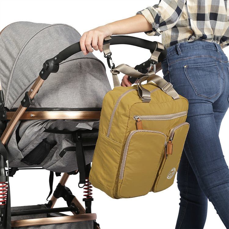 Person holding a yellow backpack next to a gray stroller on a white background