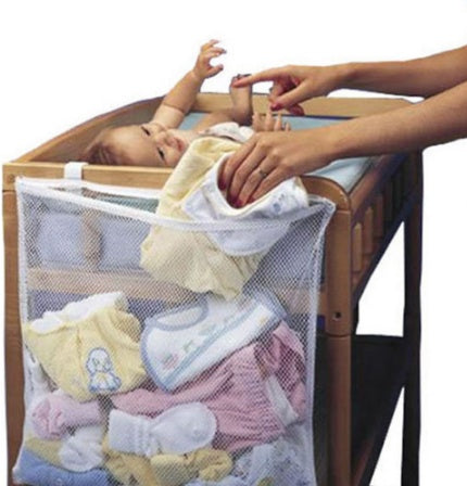 Baby lying in crib with mesh laundry bag containing baby clothes