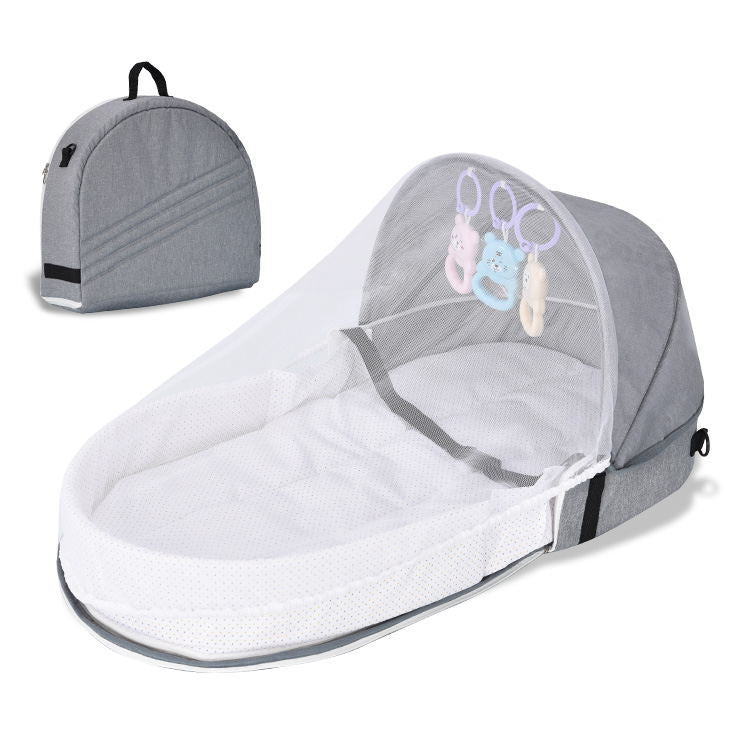 Gray and white baby bassinet with mesh cover and toy clips on a white background