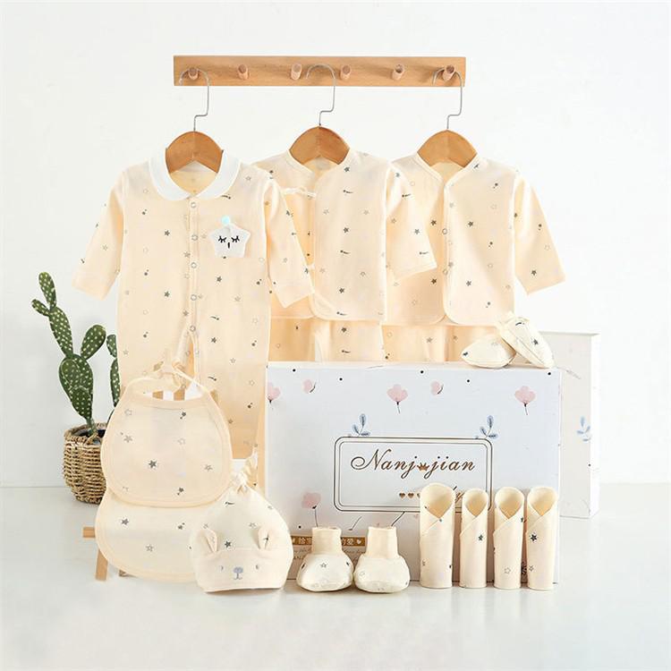 Baby clothing set with matching bag and shoes displayed on hangers against a white background.