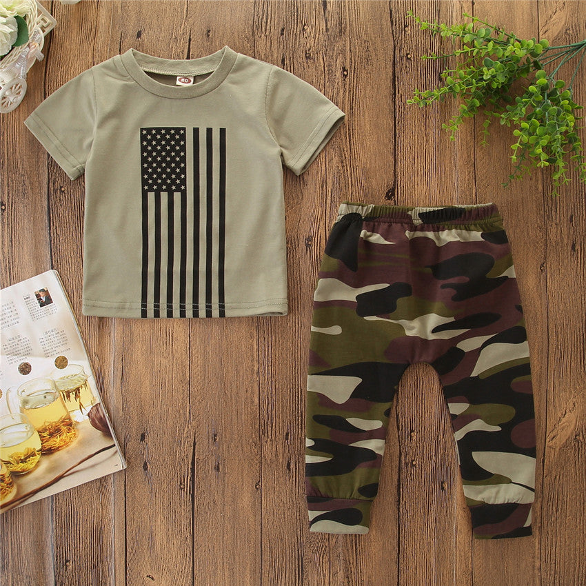 Children's outfit with American flag t-shirt and camouflage pants on a wooden surface.